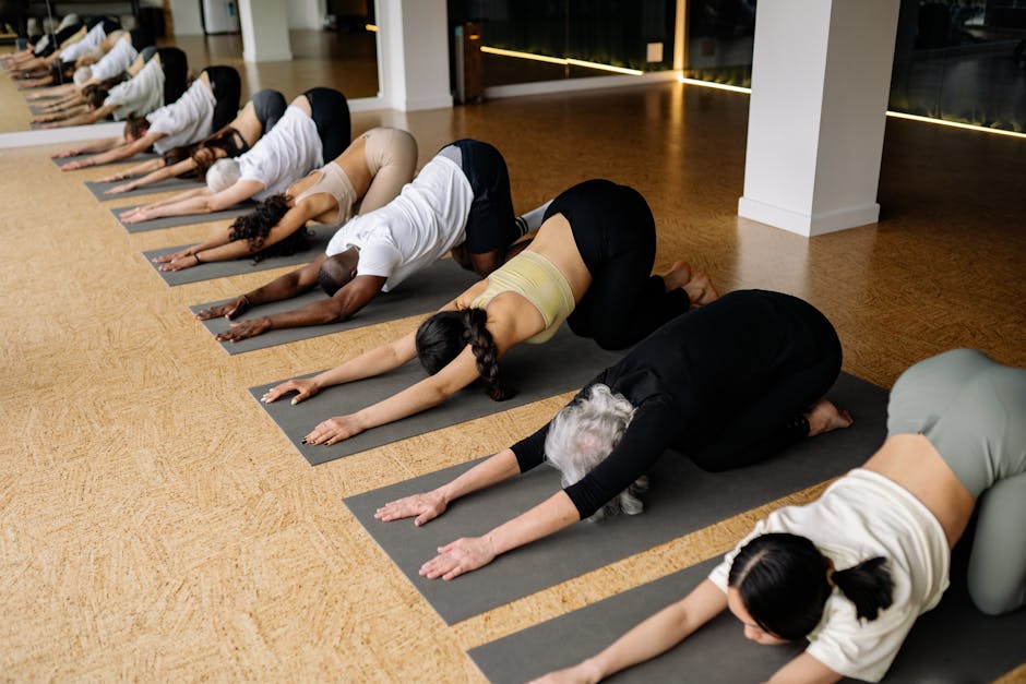 A diverse group of people of different ages and genders in a bright yoga studio.