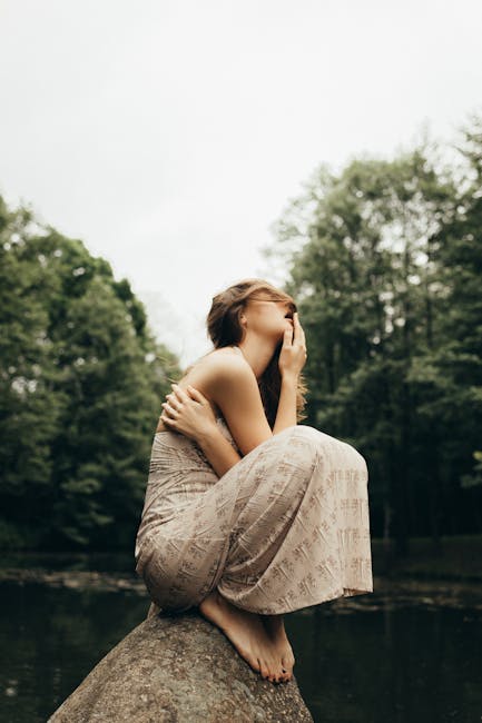 A person sitting in a calm meditative pose outdoors, with lush green nature in the background.